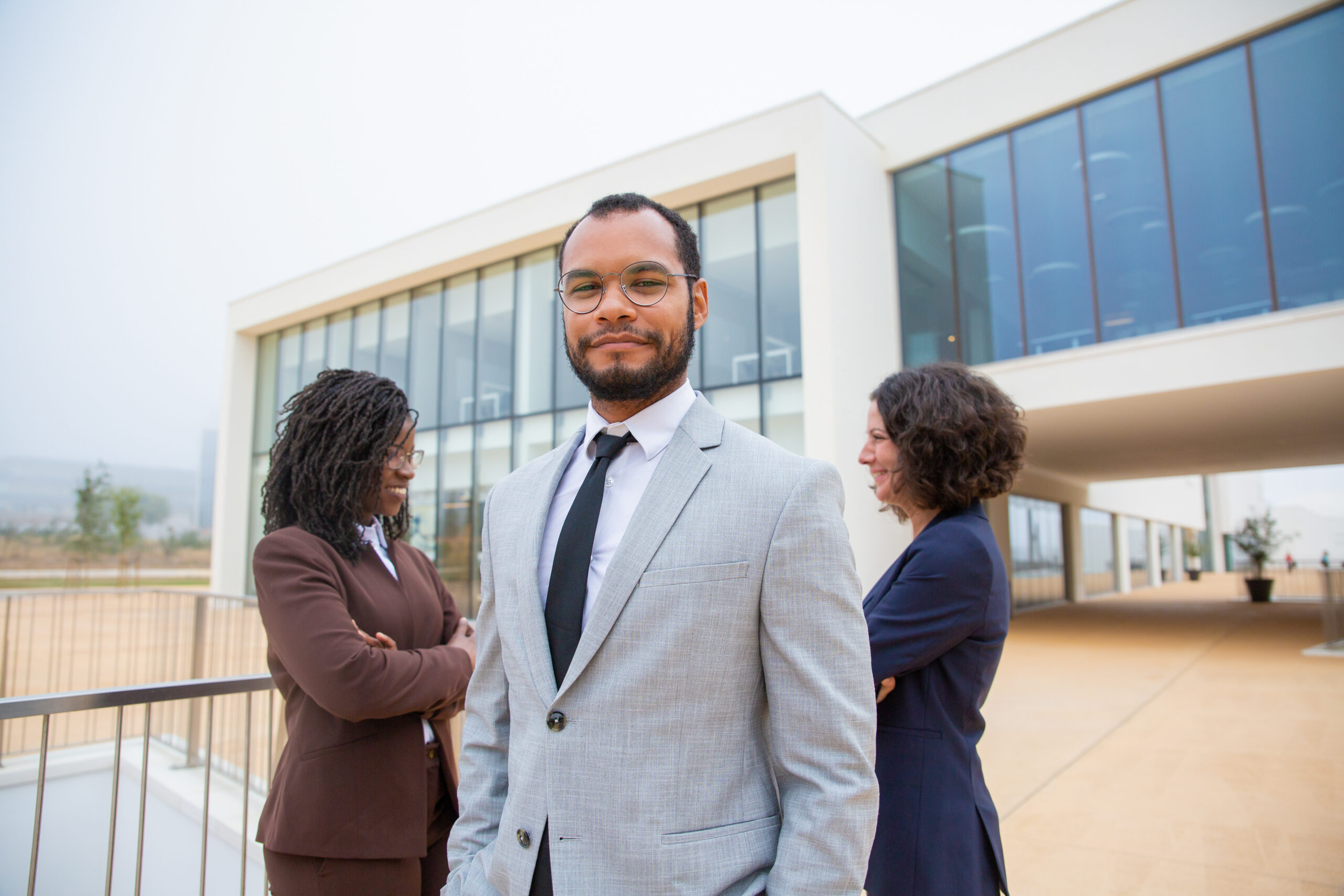 Cheerful professional business people. Multiethnic business team standing together, smiling at camera and looking at each other. Cooperation concept